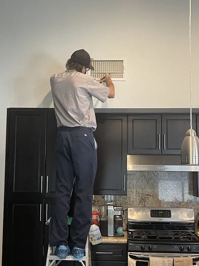 Technician inspecting an air vent during HVAC service in Jasmine Estates